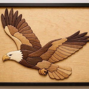 May include: Wooden wall art featuring a soaring bald eagle. The eagle is crafted from various shades of brown wood, with a white head and yellow beak. The artwork is framed in a black rectangular frame, showcasing the eagle's wingspan.