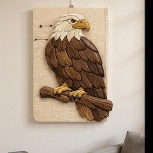 May include: A carved wooden eagle sculpture mounted on a rectangular, textured background. The eagle is depicted with white, brown, and yellow tones, perched on a brown branch. The artwork is displayed on a wall.
