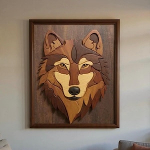 May include: Wooden wall art featuring a detailed wolf head. The artwork is crafted from various shades of wood, including light and dark browns, creating a layered effect. The wolf's eyes are a lighter shade, and the piece is framed in a dark wood.