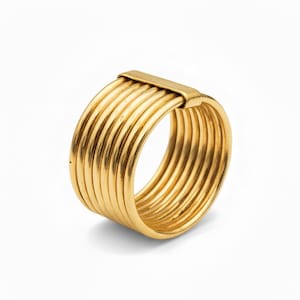 Puede incluir: Un anillo dorado con un diseño único. El anillo presenta múltiples bandas paralelas sujetas por una barra rectangular. Las bandas son lisas y brillantes, creando un aspecto audaz y elegante. El anillo está sobre un fondo blanco.