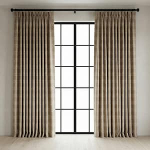 May include: Two beige plaid curtains hang on a black rod above a black-framed window. The curtains are pleated and have a subtle grid pattern. The window is divided into multiple panes, and the floor is light-colored wood.