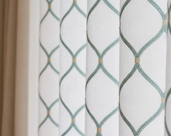 Könnte beinhalten: Weiße Vorhänge mit einem sich wiederholenden geometrischen Muster in Türkis und Beige. Das Design zeigt eine Reihe von verbundenen Rauten, die einen strukturierten und dekorativen Look erzeugen. Die Vorhänge sind aus hellem Stoff.