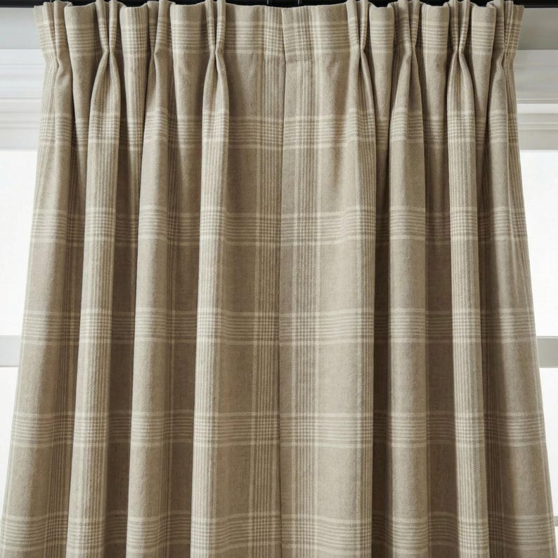 May include: Beige plaid curtain panels. The curtains are made of a thick fabric and feature a classic plaid pattern in shades of beige and off-white. The curtains are hanging from a dark rod.