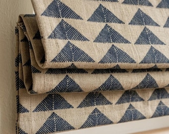 May include: Beige fabric with a repeating pattern of navy blue triangles. The fabric is folded, revealing multiple layers of the design. The triangles are filled with a textured, linear pattern.