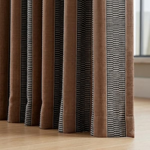Pu&ograve; includere: Un pannello per tenda a tutta altezza caratterizzato da strisce verticali in tonalit&agrave; alternate di marrone e un motivo geometrico grigio scuro e bianco. Il tessuto presenta una trama visibile e cade in pieghe profonde e strutturate, creando un motivo ritmico.