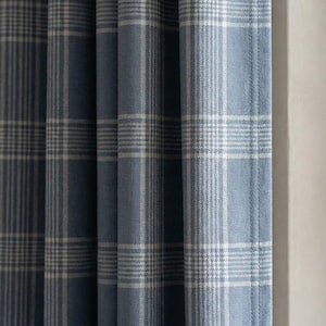 May include: Blue and white plaid curtains. The fabric has a soft texture and a classic plaid pattern. The curtains are hanging, with vertical folds visible. The color scheme is a light blue and white.