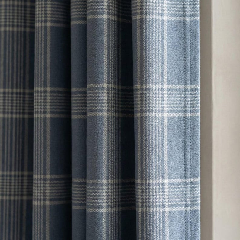 May include: Blue and white plaid curtains. The fabric has a soft texture and a classic plaid pattern. The curtains are hanging, with vertical folds visible. The color scheme is a light blue and white.
