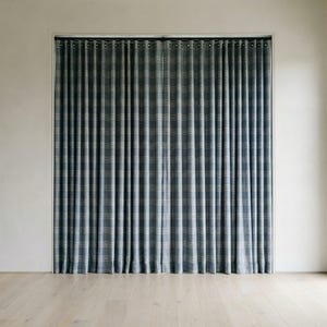 May include: A pair of blue and white plaid curtains hanging in a window. The curtains are made of a textured fabric and have a classic, elegant design. The curtains are hanging in front of a white wall and a light-colored wooden floor.