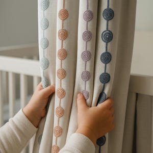 May include: Cream-coloured curtains featuring embroidered circular patterns in pastel shades of blue, peach, and lilac. The curtains are held open, revealing a white cot in the background. The design is a decorative element.