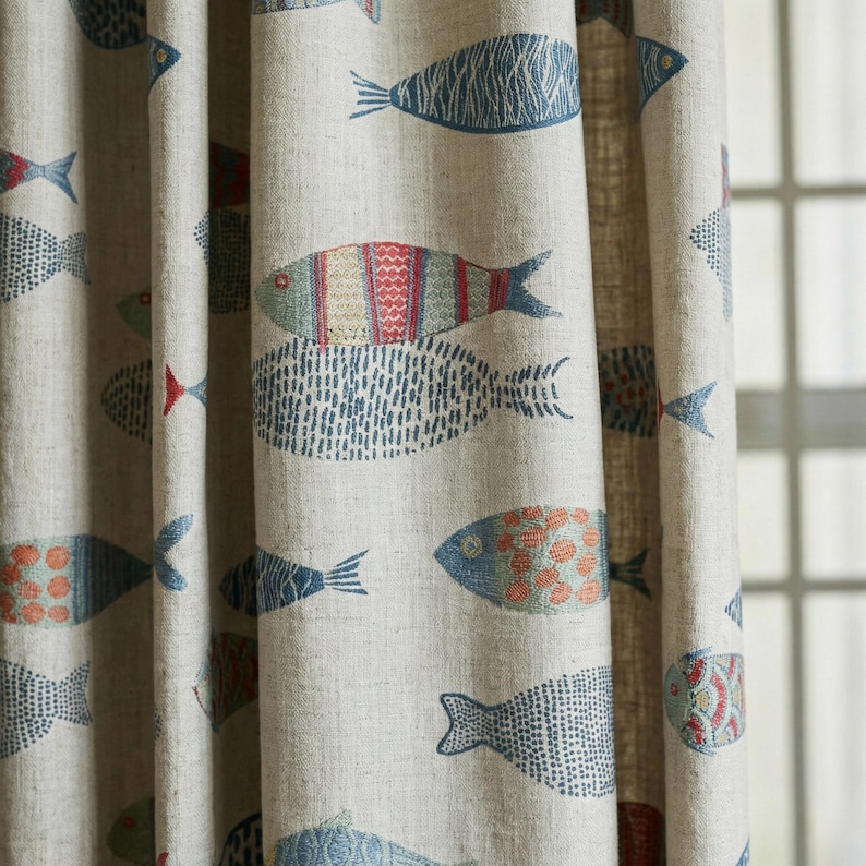 May include: Beige fabric curtain with a repeating pattern of stylized fish in shades of blue, red, and orange. The fish designs vary in pattern and size, creating a whimsical, nautical theme. The curtain is made of a textured fabric.