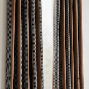 Pu&ograve; includere: Due pannelli per tende a tutta altezza caratterizzati da un motivo a righe verticali. Il design &egrave; composto da un'alternanza di ampie fasce marroni a tinta unita e fasce pi&ugrave; strette con micro-righe grigio scuro e bianco, creando una texture.