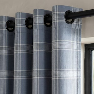 May include: Blue plaid curtains with black grommets hanging from a black curtain rod. The curtains have a light blue background with a white plaid pattern. The curtains are hanging in front of a window.