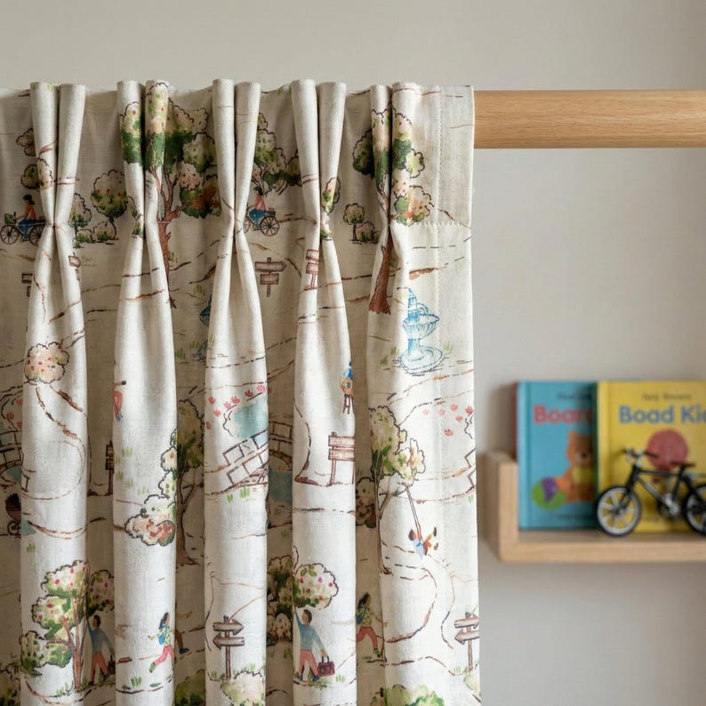 May include: Cream-colored curtain panels with a whimsical park scene print. The design features trees, people, bicycles, and a fountain in shades of green, blue, and brown. The curtains are hanging on a wooden rod.