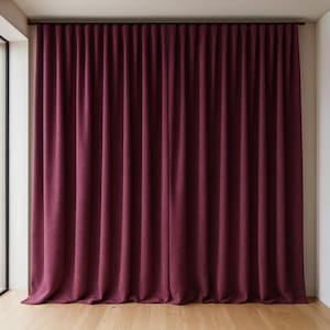 May include: Full-length, deep burgundy curtains suspended from a black rail. The curtains have a textured finish and are gently pleated, forming vertical lines. The material looks thick and opaque, ideal for light blocking.