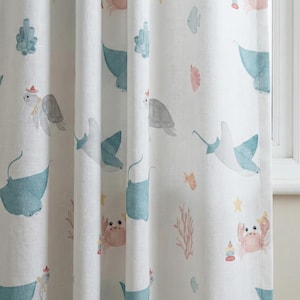 May include: White curtain panel with a playful watercolour design of marine life. The pattern includes turtles, stingrays, crabs, fish, and coral in blue, pink, and yellow. The curtain is made of a light-coloured fabric.