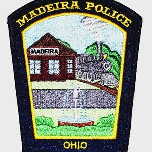 May include: Embroidered patch featuring the words "MADEIRA POLICE" in gold lettering. The patch depicts a train, a building with the word "MADEIRA", and a fountain. The word "OHIO" is at the bottom. The patch has a navy blue border.