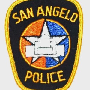 May include: A San Angelo Police patch with a black background and a yellow border. The patch features the words "SAN ANGELO POLICE" in yellow. Inside is a white star, orange and blue sections.