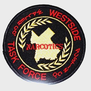 May include: A round black embroidered patch with red and yellow text. The patch reads "WESTSIDE AUSTIN" and "TASK FORCE 90" around the outer edge. The center features a yellow map outline and the word "NARCOTICS".