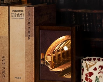 Puede incluir: Un rincón de libro de madera con una escena interior detallada e iluminada de un arco de ladrillo y escaleras. El rincón de libro está colocado entre varios libros, incluido uno con el título "Country Strong."