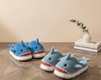 Può includere: Quattro paia di pantofole a forma di squalo blu con suole bianche e bocche rosse e bianche. Le pantofole hanno una consistenza morbida e soffice e sono progettate per assomigliare agli squali. Le pantofole sono un'opzione di calzatura divertente e accogliente.