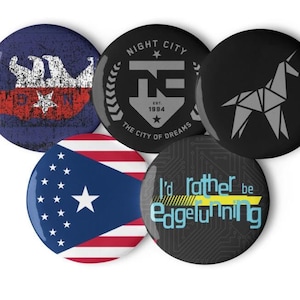 Op de afbeelding: Vijf ronde zwart-witte knoppen met verschillende ontwerpen. De eerste knop heeft een blauw en wit verweerd ontwerp met een ster in het midden. De tweede knop heeft een zwart-wit ontwerp met de tekst "Night City Est. 1994 The City of Dreams" en een gestileerde letter "N". De derde knop heeft een zwart-wit origami-eenhoornontwerp. De vierde knop heeft een rood-wit-blauw ontwerp met een ster in het midden. De vijfde knop heeft een zwart-wit ontwerp met de tekst "I'd rather be Edgerunning".