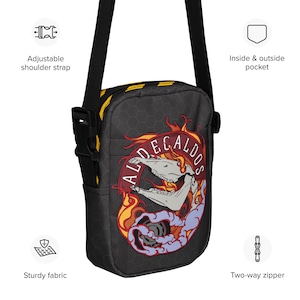 Puede incluir: Bolso bandolera negro con un gráfico de calavera y llamas, con el texto "ALDECALDOS". Cuenta con una correa ajustable para el hombro, cremallera bidireccional y bolsillos interiores y exteriores. Fabricado con tejido resistente.