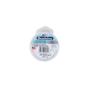 Pode incluir: Um carretel de fio para contas Beadalon. O rótulo indica 49 fios, 9,2 m de fio e um diâmetro de 0,46 mm. A embalagem inclui texto em inglês e espanhol.