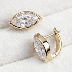 Può includere: Un paio di orecchini a cerchio in oro con pietre trasparenti taglio marquise. Ogni orecchino presenta una montatura in oro lucido e una chiusura a cerniera. Sul lato dell'orecchino è inciso il testo 0.75ct, che indica il peso in carati.