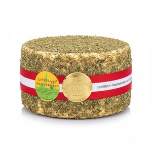 Könnte beinhalten: Runder Käse, bedeckt mit Kräutern, mit einem rot-weißen Band. Er hat ein goldenes Siegel mit "KASARMANDL GOLD 2023" und einen gelben Aufkleber "Langenegger Kräuterkäse". Der Käse hat eine hellgelbe Farbe.