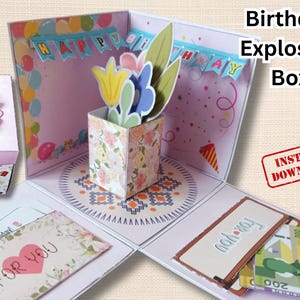 Pode incluir: Uma caixa de explosão de aniversário de papel com um cubo central de padrão floral, flores de papel, uma tampa de margarida rosa e painéis interiores decorados com balões, confetes e faixas com os dizeres Happy Birthday e For You.