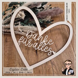 May include: A wooden heart-shaped decoration with the words "Danke für alles" in cursive script. The heart is light-colored and sits on a wooden surface. Dried flowers are visible in the background. The bottom of the image has the text "Digitale Datei".
