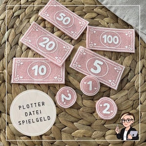 May include: Pink felt play money with white numbers and heart details. Includes bills with denominations of 5, 10, 20, 50, and 100, plus coins marked 1 and 2. A wooden circle with text is also present.
