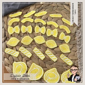 May include: Yellow felt pasta shapes with white stitching, including bow ties, shells, and penne, arranged on a woven mat. The image includes the text "Digitale Datei .SVG | .studio3".