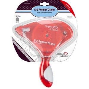 May include: A red and white E-Z Runner Grand adhesive dispenser with a roll of white permanent adhesive tape. The dispenser is labeled "Scrapbook Adhesives" and "E-Z Runner Grand".