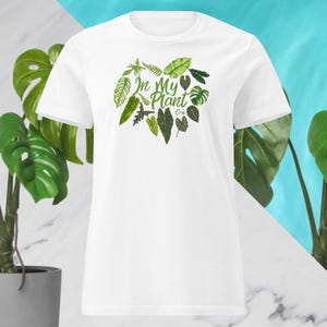May include: White t-shirt featuring a watercolor design of various green leaves and the text "In My Plant Era". The design is centered on the chest. The shirt has short sleeves and a crew neck.