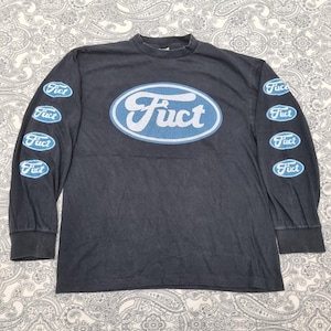 May include: Black long-sleeve shirt with the word "Fuct" in a blue and white oval on the front. The sleeves have the word "Fuct" in blue and white ovals. The shirt is made of a soft, comfortable material.