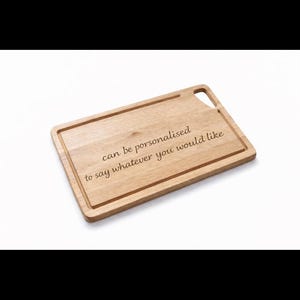 May include: A rectangular wooden cutting board with a handle cutout. The text "can be personalised to say whatever you would like" is engraved on the board. The board is light brown in color.