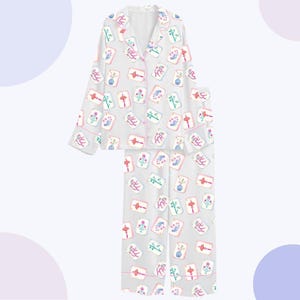 May include: A light gray pajama set featuring a repeating pattern of colorful floral and decorative card illustrations. The set includes a button-down top with pink trim and matching pants. The pajamas are made of a soft, lightweight fabric.