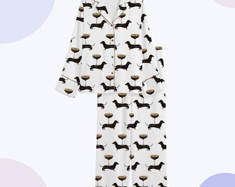 May include: White pajama set with a repeating pattern of black dachshunds and champagne glasses. The long-sleeved top has a collared neckline and button-down front. The pajama pants have a straight leg design.