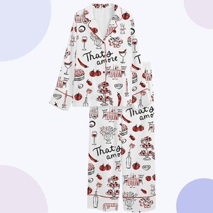 May include: White pajama set with a repeating pattern of red and black Italian food illustrations, including wine glasses, cakes, and tables. The words "That's amore" are printed on the shirt and pants.
