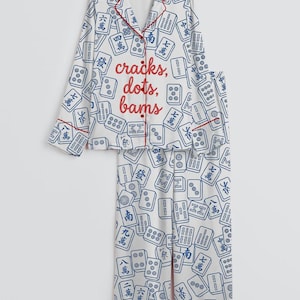 May include: White pajama set with a blue Mahjong tile pattern and red trim. The top features the text "cracks, dots, bams" in red. The set includes a button-down shirt and matching pants.