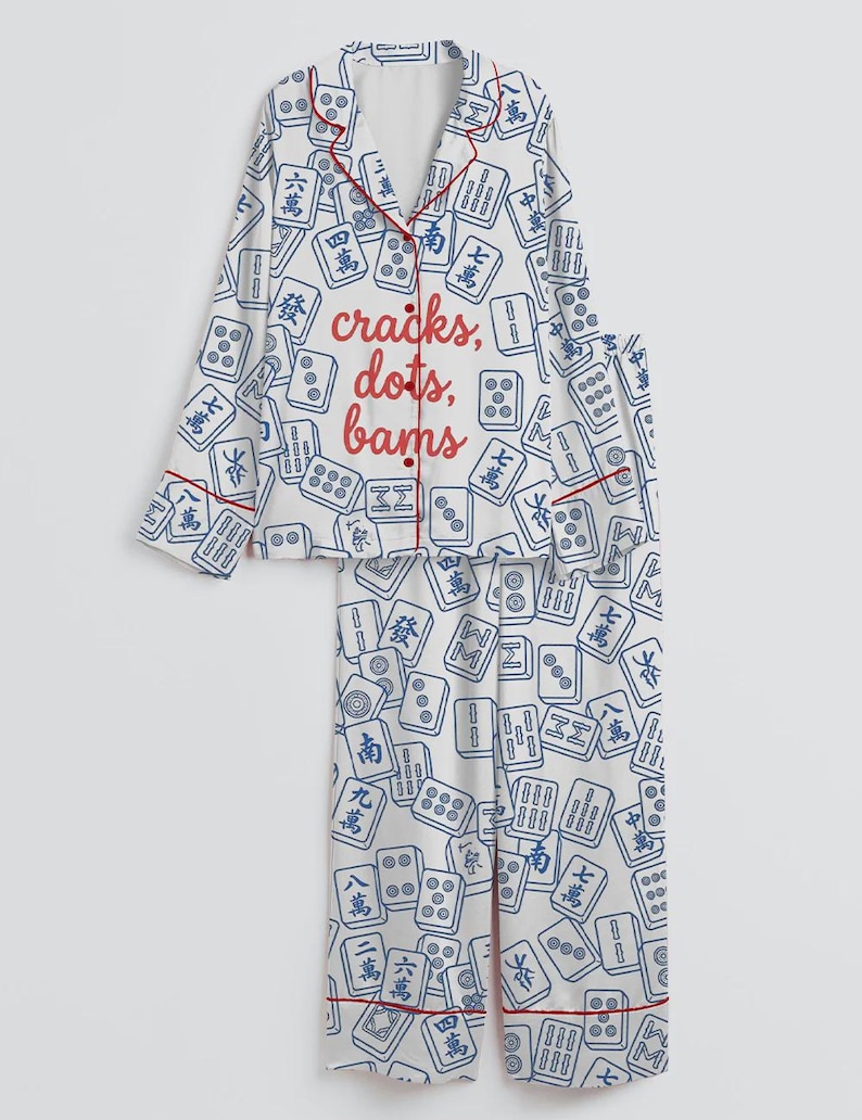 May include: White pajama set with a blue Mahjong tile pattern and red trim. The top features the text "cracks, dots, bams" in red. The set includes a button-down shirt and matching pants.