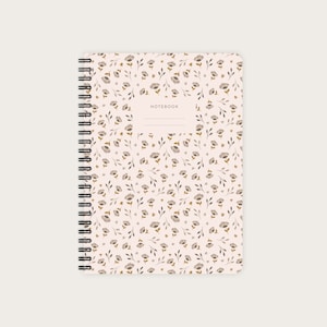 Könnte beinhalten: Ein rosa Notizbuch mit einem Blumenmuster in Braun- und Grautönen. Das Notizbuch hat eine Spiralbindung und das Wort "NOTEBOOK" ist auf dem Einband aufgedruckt.