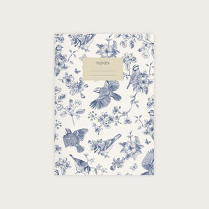 Könnte beinhalten: Ein weißer Notizbuchumschlag mit einem blauen und weißen Blumenmuster mit Vögeln. Der Umschlag hat ein Etikett mit der Aufschrift "NOTEBOOK".