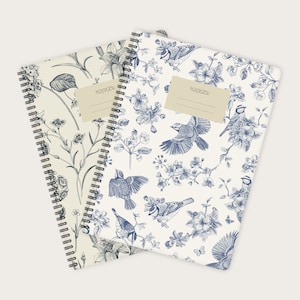 Könnte beinhalten: Zwei spiralgebundene Notizbücher mit weißem Hintergrund und blauen Blumen- und Vogelmotiven. Der Text "NOTEBOOK" ist auf der Vorderseite jedes Notizbuches gedruckt.