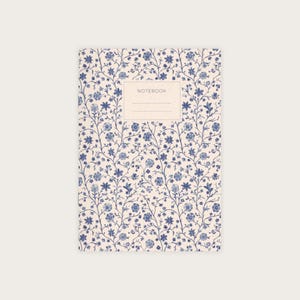 Könnte beinhalten: Ein weißes Notizbuch mit einem blauen Blumenmuster und dem Wort "NOTEBOOK" auf dem Einband.