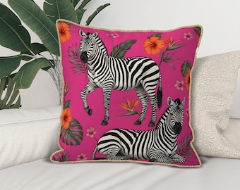 May include: A decorative square pillow with a vibrant pink background featuring two zebras. One zebra is standing, the other is lying down. The pillow is adorned with orange flowers, green leaves, and a gold trim.