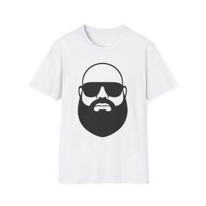 May include: White t-shirt featuring a black graphic of a bald head, sunglasses, and a full beard. The design is centered on the front of the shirt. The shirt has a crew neck and short sleeves.