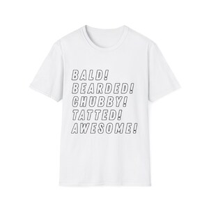 Puede incluir: Camiseta blanca con texto negro: BALD! BEARDED! CHUBBY! TATTED! AWESOME! La camiseta tiene cuello redondo y mangas cortas. El texto está en negrita, fuente sans-serif.