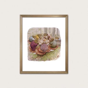 May include: A framed print featuring a whimsical illustration of anthropomorphic frogs gathered around a table set on a mushroom. The frogs, dressed in various colors, appear to be having a tea party in a forest setting. The print is in a gold frame.